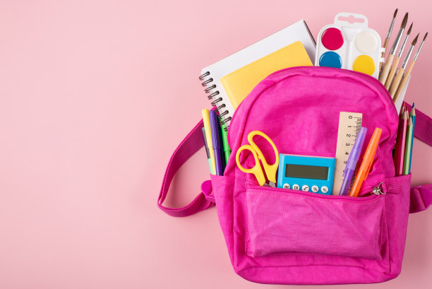 顶部上方俯瞰照片的粉红色背包和彩色文具放置在右侧孤立在柔和的粉红色背景与copyspace图片下载