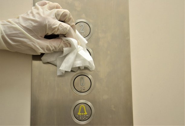 新型冠状病毒肺炎预防清洁女工用抗菌消毒纸巾擦拭电梯按钮，以杀灭接触表面的冠状病毒。图片下载