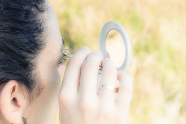 一个女孩在镜子前拔眉毛的特写图片下载