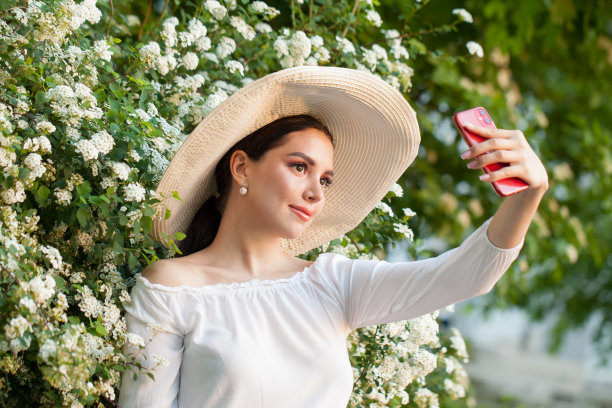 手持鲜花的美女用智能手机自拍并通过社交媒体分享照片图片下载