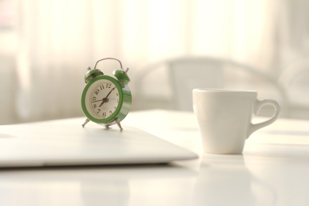 闹钟上有一杯咖啡，桌上有一台笔记本电脑。图片下载
