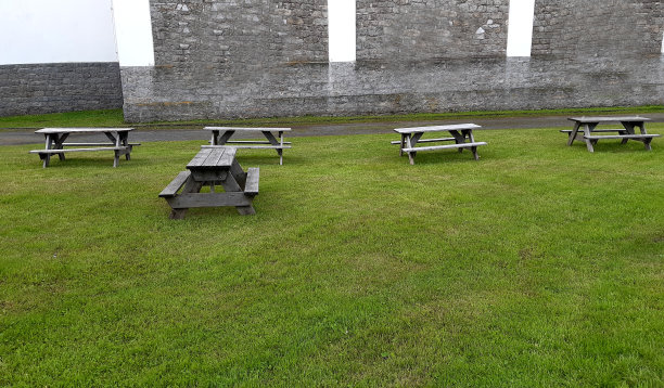 公园露营长椅由灰色的天然云杉木材在一个草地在一个古老的石墙前图片下载