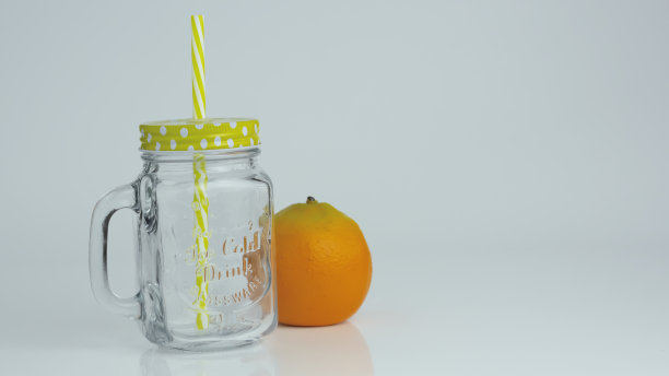 一个装着稻草的空罐子，后面放着一个橙子图片下载