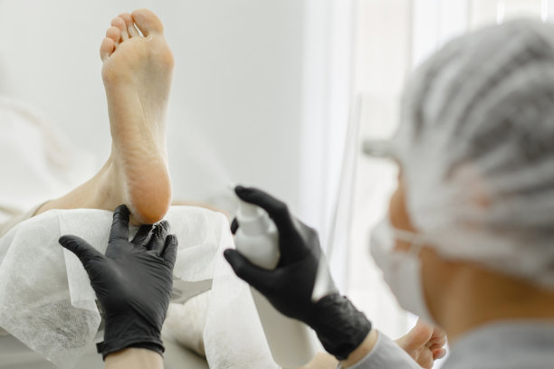 专业修脚的过程。一个戴着防护面具的师傅给女性的腿按摩。图片下载