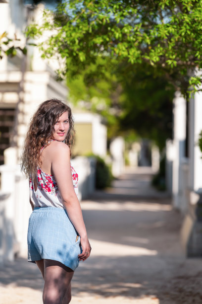 海边的佛罗里达白色的海滩建筑背景与年轻的女人女孩快乐地在阳光灿烂的日子穿着柔和的衣服在镜头前回头看图片下载
