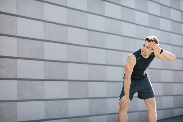 运动的生活。疲惫的人在灰色的墙壁上擦拭着汗水图片下载