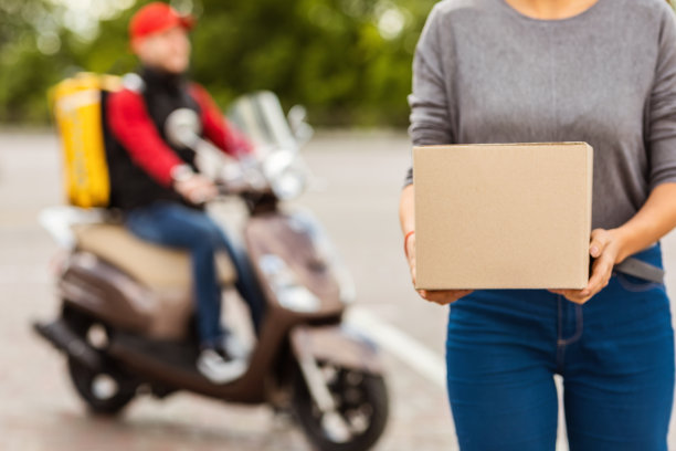 女顾客拿着包裹盒子站在外面，裁剪图片下载