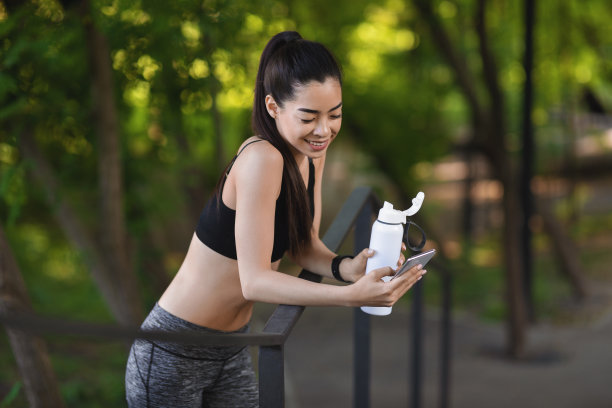 亚洲运动女性跑步后在户外休息，使用智能手机和饮用水图片下载
