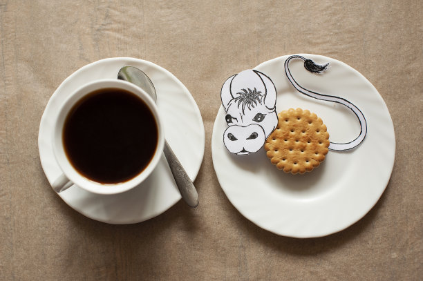 照片的静止生活的一杯咖啡与圆形饼干和一个米色的背景上画的公牛图片下载