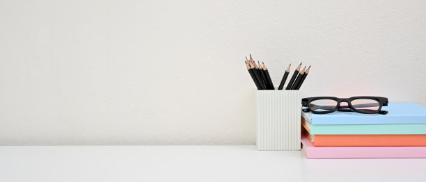 前视图的办公桌工作空间与书，眼镜和铅笔在白色的背景。空白的空间。家庭办公室的概念。图片下载