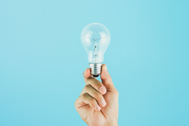 手持灯泡在蓝色背景。观念对新思想具有创新和创造力。图片下载
