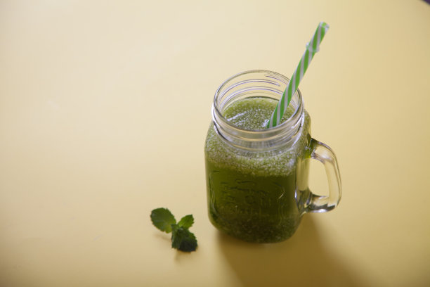 绿色清凉新鲜的香草冰沙在一个罐子，用吸管在黄色的背景。图片下载