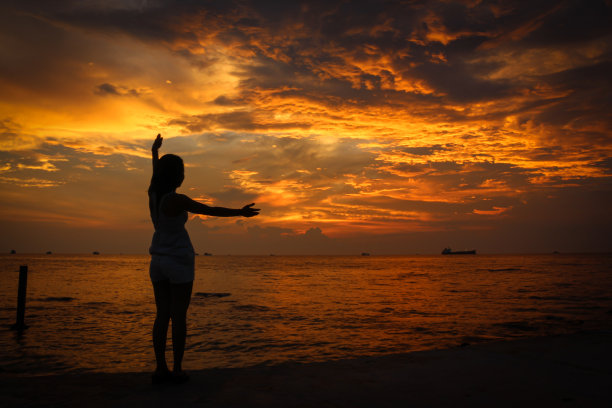 在巴乔海滩上，一个女性模特的剪影控制着云的运动图片下载