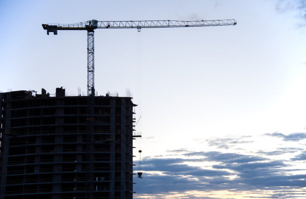 夕阳下塔吊的剪影。准备将一桶混凝土倒进模板。建设住宅楼。锐度小，可能粒度小图片下载