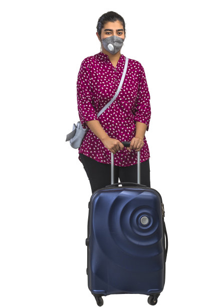 一名女学生带着吊带包和行李箱旅行，脸上戴着n95口罩图片下载