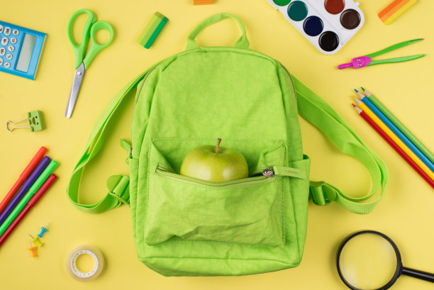 健康饮食在学校的概念。上面俯瞰苹果绿色背包的照片彩色文具孤立在黄色的背景图片下载