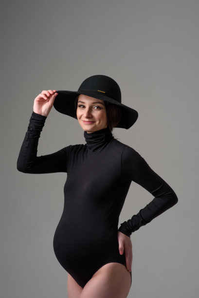 年轻漂亮的孕妇穿着黑色紧身衣，戴着帽子。图片下载