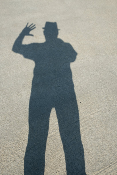 一个戴帽子的男人的影子在水泥地板上。图片下载