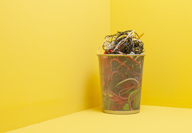 垃圾桶内有大量堆叠的电缆，以黄色背景隔离图片下载