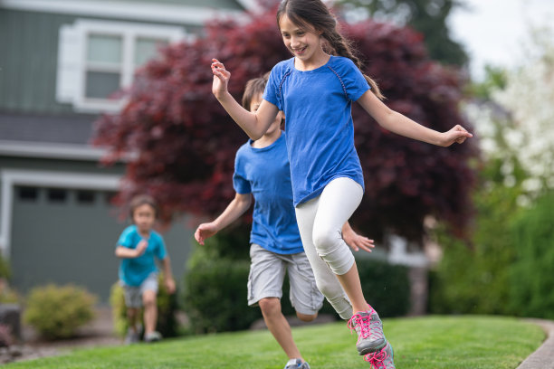 三个孩子在外面跑过一片草地图片下载