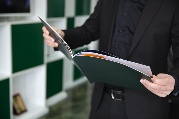 商人在黑色西装阅读印刷演示。图片下载