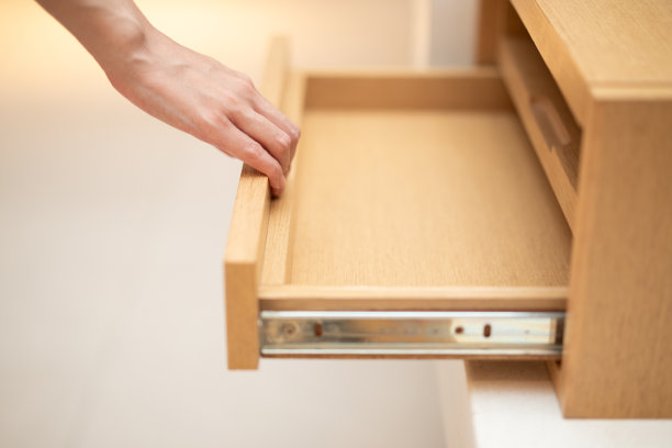 女人用手拉开木柜的抽屉。图片下载