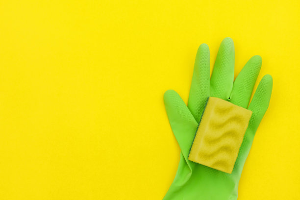 绿色手套和黄色海绵清洁黄色背景。图片下载