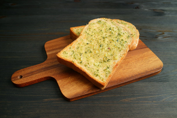 两个酥脆可口的自制蒜蓉黄油吐司放在木板上图片下载