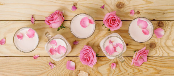 木桌上放着玫瑰和月光牛奶。阿育吠陀放松的夜晚饮料。图片下载