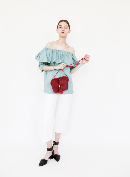 美丽的年轻女子穿着时尚的衣服和红色的设计师包时装模特工作室肖像在白色的背景图片下载