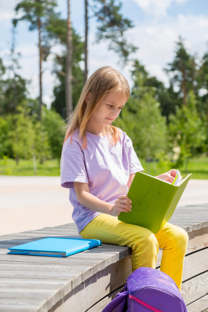 专注的中学女孩在公园看书图片下载