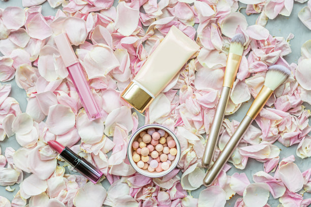 粉色玫瑰花瓣上的化妆品。平躺，俯视图图片下载