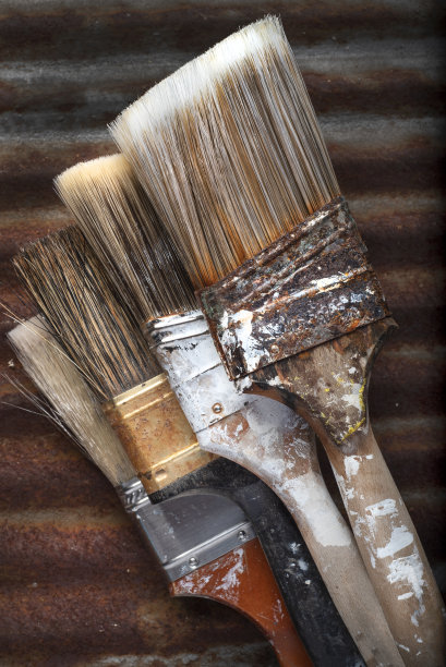 四个旧的脏刷子在生锈的金属背景上图片下载