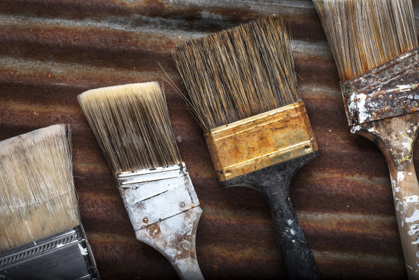 四个旧的脏刷子在生锈的金属背景上图片下载
