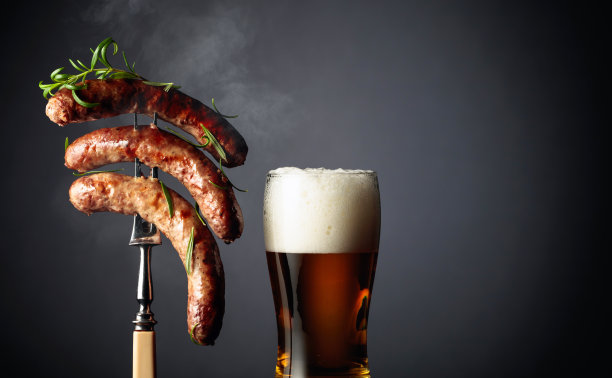 啤酒和迷迭香烤巴伐利亚香肠。叉子上撒着迷迭香的香肠。图片下载
