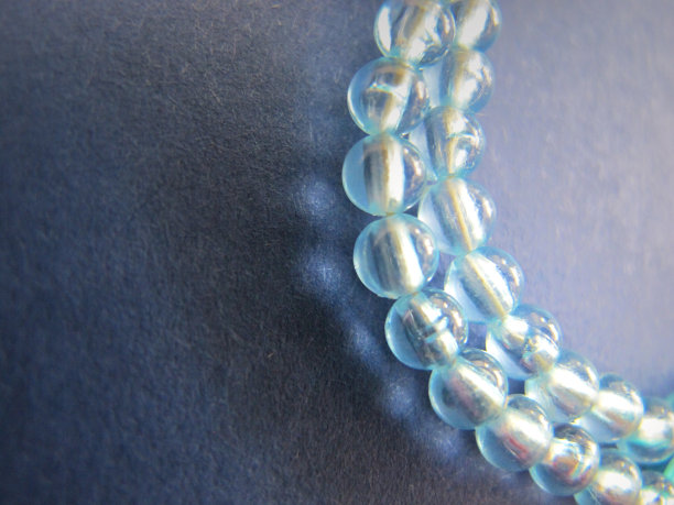 蓝绿色透明的珠子或珍珠，像在蓝色背景上的水滴。图片下载