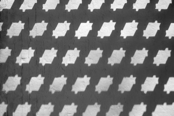 几何的影子从古老的雕刻门上粗糙的白墙上，黑白的照片图片下载