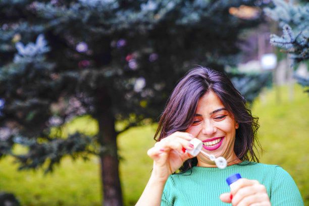 快乐的美女在室外吹肥皂泡图片下载