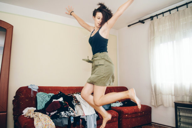 快乐的女孩戴着耳机跳在她的房间库存照片图片下载