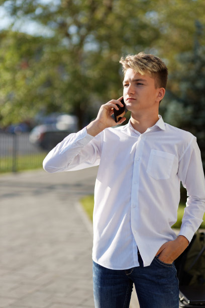 一个年轻人在街上用智能手机聊天的照片。浅的焦点。图片下载