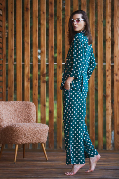 女人站在睡衣睡衣与波尔卡点在木制背景在全长。白人女性模式。图片下载