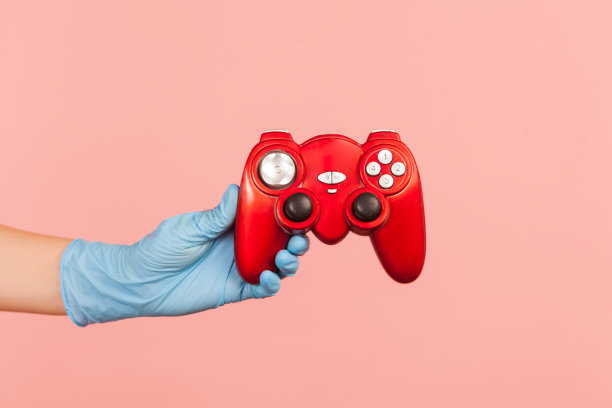 侧面特写的人的手在蓝色的外科手套拿着红色的游戏手柄。图片下载
