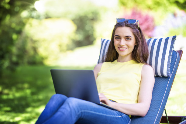 年轻女子在家工作时在花园里使用笔记本电脑图片下载