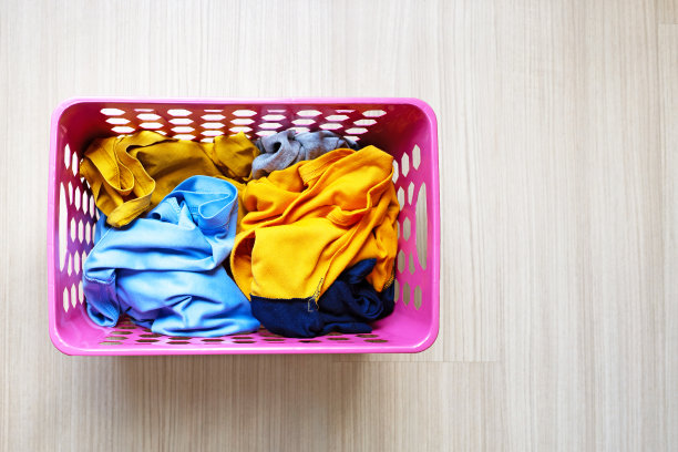 衣服放在粉红色的塑料洗衣篮里。衣服的概念图片下载