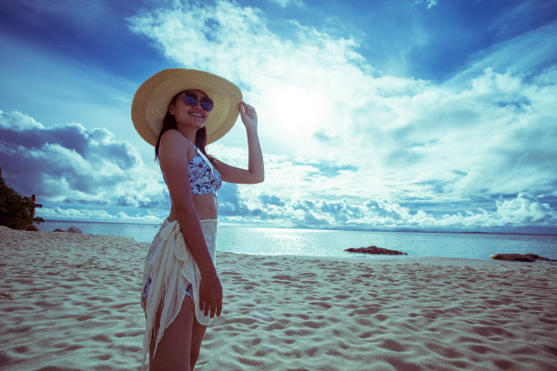 一名亚洲女子在晴朗的日子穿着比基尼和海帽在沙滩上图片下载