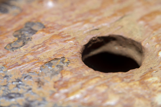 背景与旧金属表面生锈和剥落油漆。金属板上有锯齿孔。照片与软焦点和模糊背景在高倍放大。图片下载