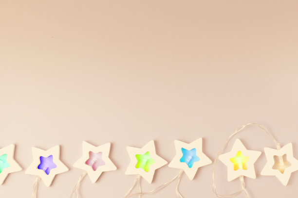 星星的花环与彩色的灯在米色的表面作为圣诞或新年的节日背景。俯视图，平放，文本的位置，复制空间。图片下载