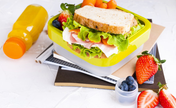 盒装学校午餐和一瓶果汁。三明治配奶酪和沙拉，新鲜浆果做婴儿食品。浅色背景和文本空间。副本的空间。高质量的照片图片下载