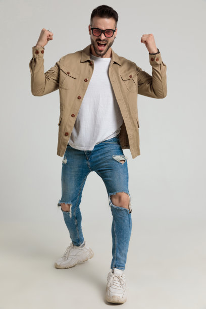 穿着夹克的热情的年轻人在空中挥舞着拳头图片下载