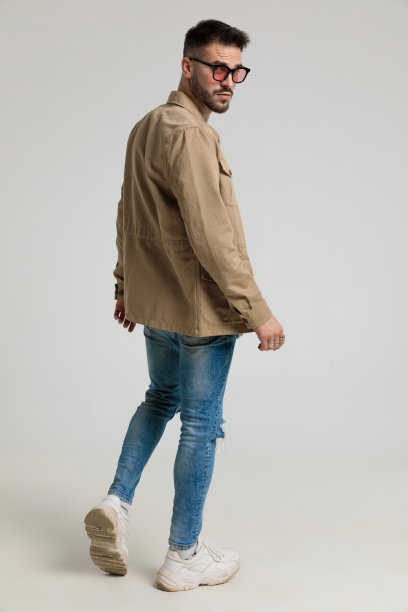 酷年轻的时尚模特在夹克戴着太阳镜和摆姿势图片下载